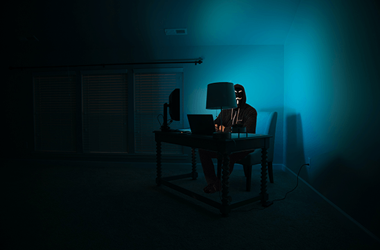 Hacker at a computer in a dark room.