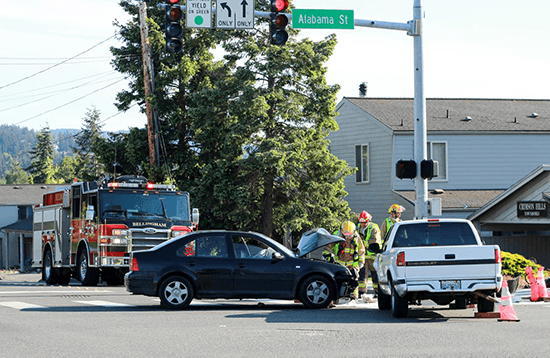 Two cars involved in a collision at an intersection with fire department on scene.