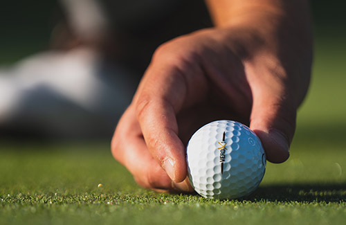 Closeup of a hand grabbing a golf ball.