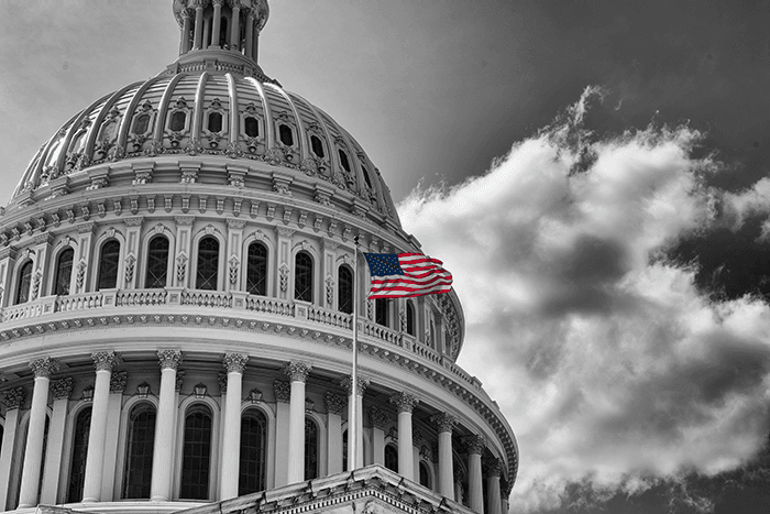 American flag waving in front of the US Capitol building.