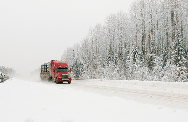 A red semi truck driving down a snowy road.