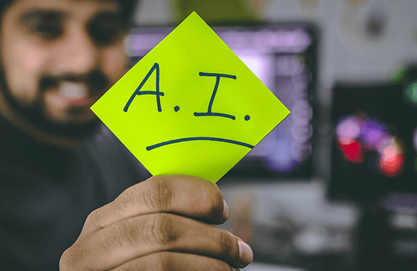 Sticky note with A.I. written on it held by a blurred man.