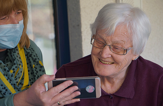 Nurse showing older woman cell phone.