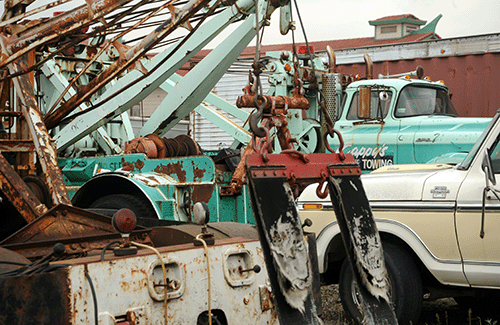 Tow truck equipment at a yard with other trucks in the background.