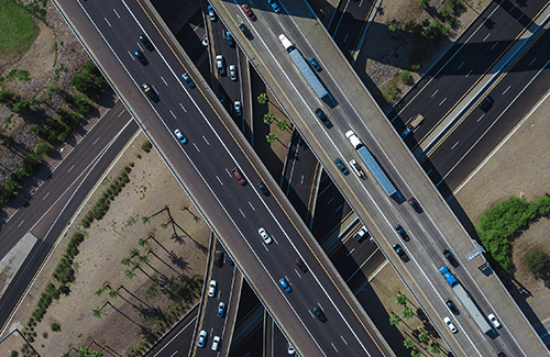 Aerial view of overlapping freeways with a lot of cars and large trucks driving.