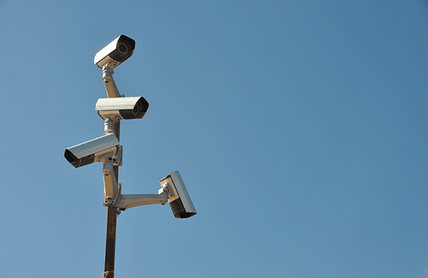 A security camera is shown against a blue sky.